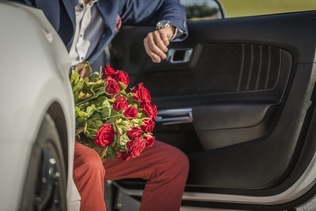 Imagem de um homem com um buquê de rosas sentado em um carro
