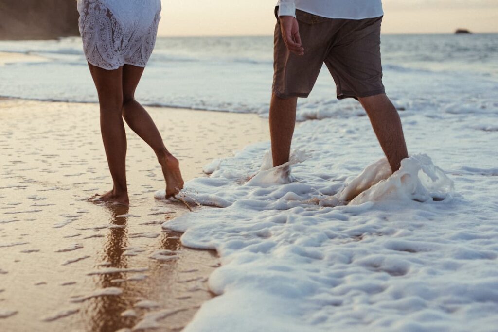Imagem de um casal andando na praia do lado do mar