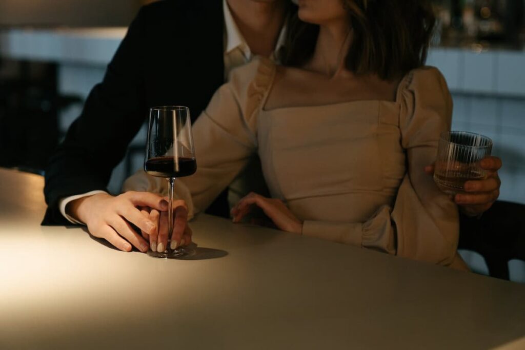 Imagem de um casal tomando vinho abraçados