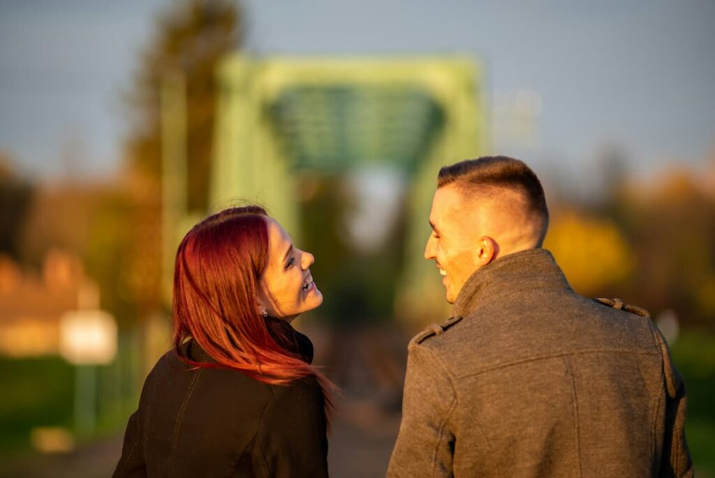 Imagem de um casal rindo em uma ponte em um dia de sol
