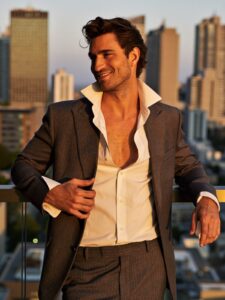 Homem charmoso na faixa dos 40 anos, elegante, em um rooftop ao pôr do sol
